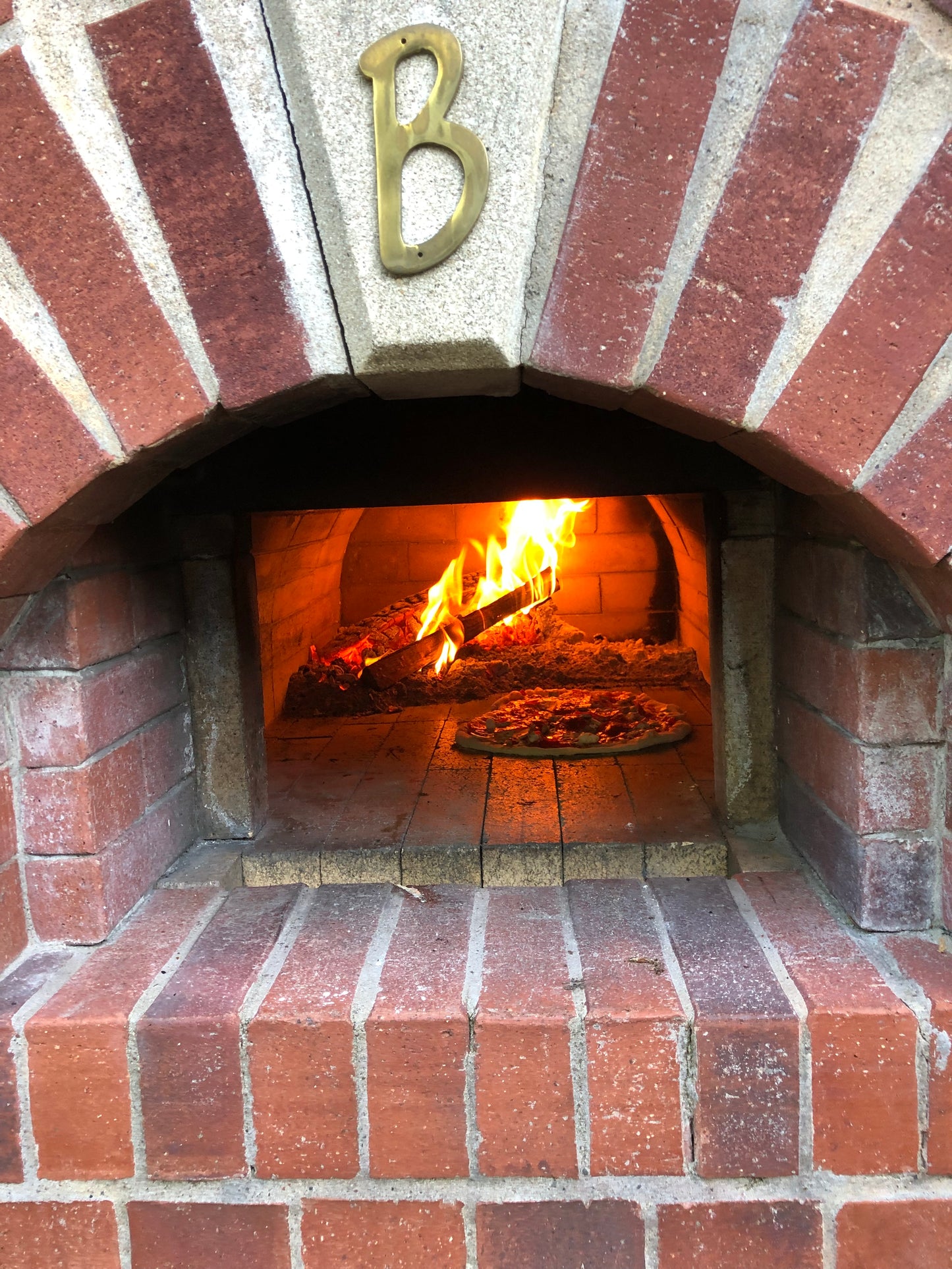 fire in pizza oven with a pizza cooking