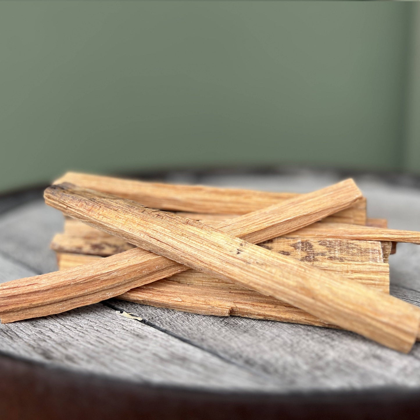 Stack of wooden fatwood sticks on a textured surface with a blurred green background