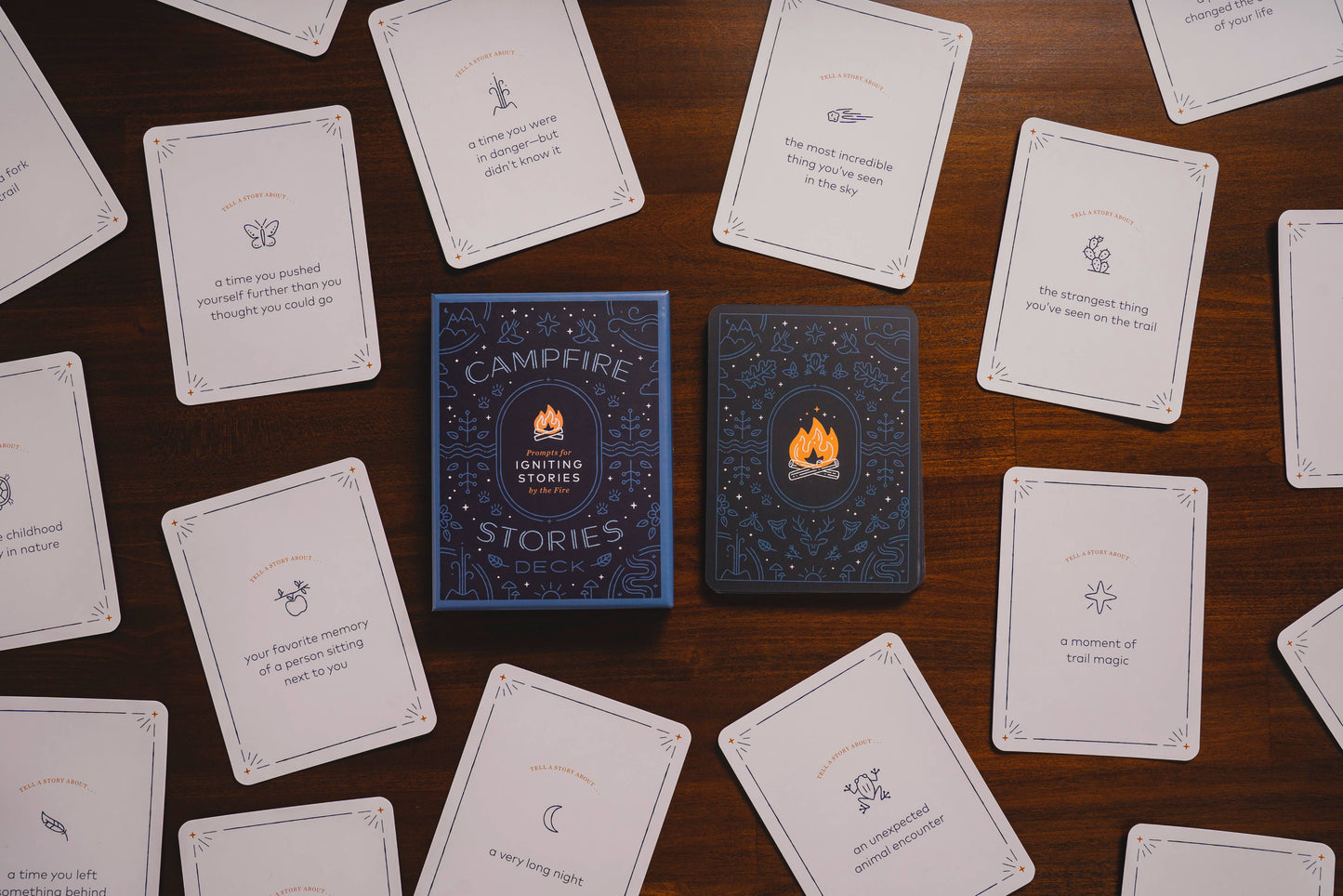 Two blue books titled 'Campfire' and 'Stories' surrounded by white cards on a wooden surface.