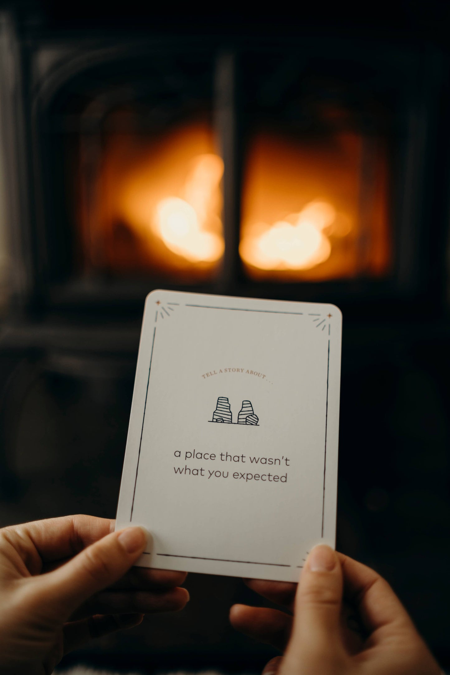 Person holding a playing card with text in front of a fireplace